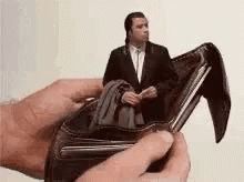 a person is holding a wallet with a picture of a man in a suit in it .